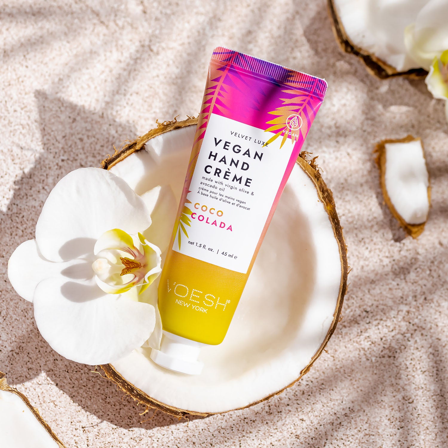 Coco Colada Oasis Vegan Hand Crème inside of a coconut on a sand background.